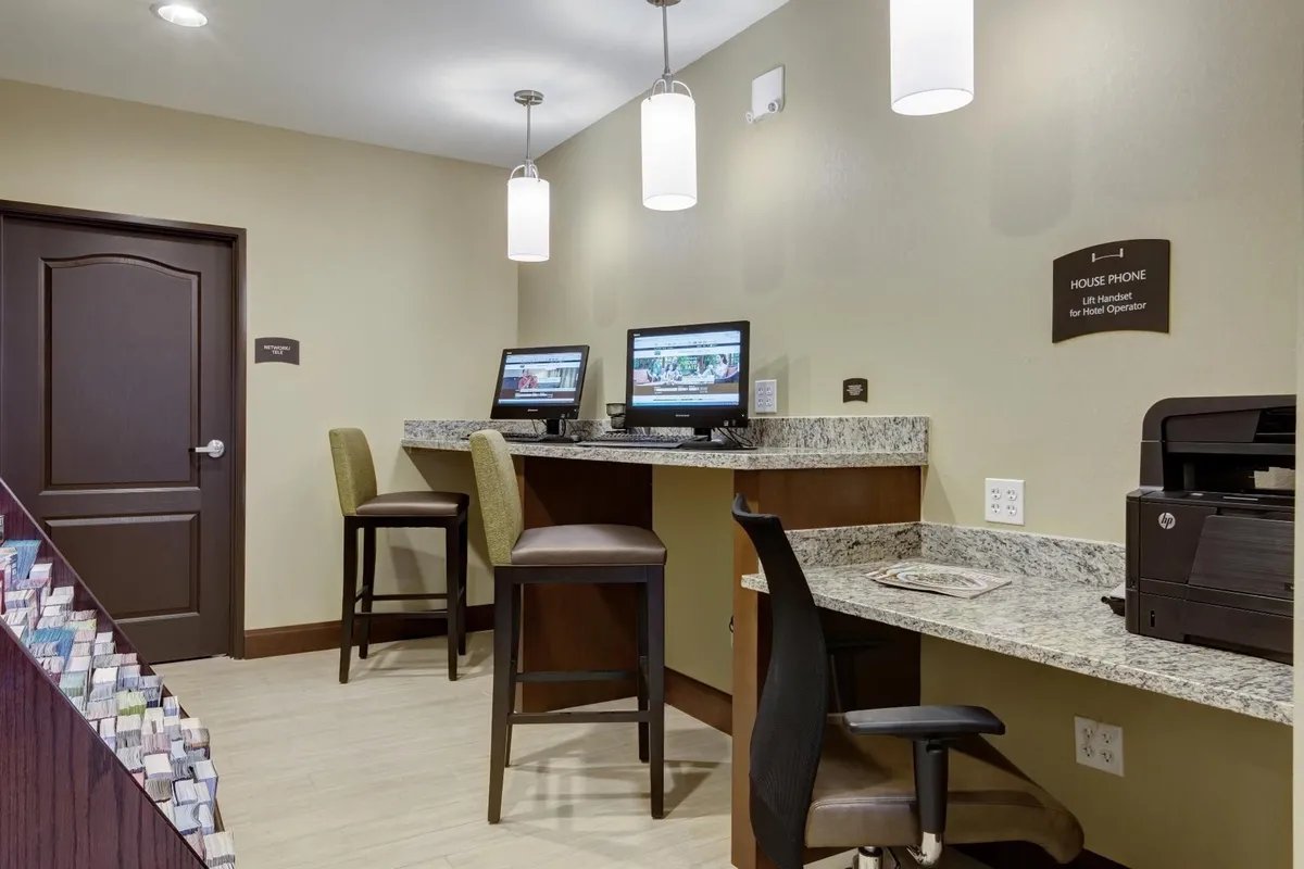 A compact business center with computers, bar stools, a granite countertop, and a house phone, providing guests with an efficient, professional environment for work-related needs.
