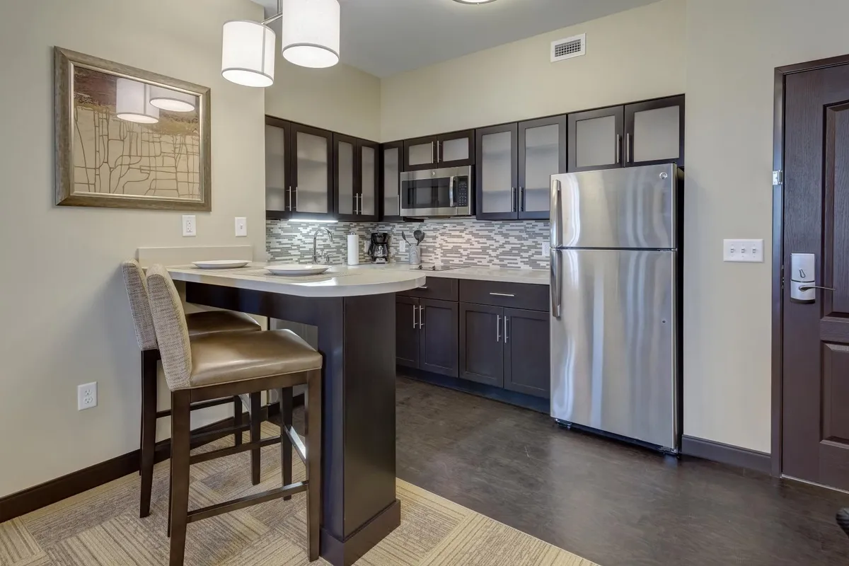 A chic open-concept bar seating area with stainless steel appliances and a textured backsplash. The space is designed for both functionality and style, offering a welcoming environment for casual dining, cooking, or entertaining guests.